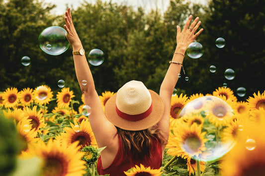 femme qui leve les bras au ciel dans un champs de tournesol