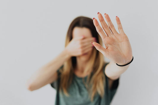 femme qui dit stop de la main en se cachant le visage
