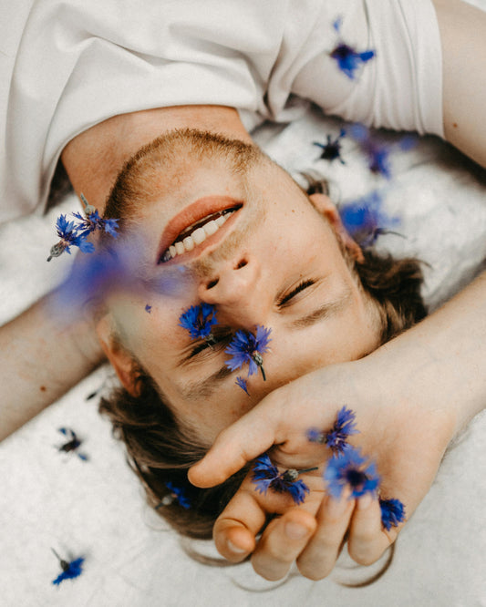 homme allongé a qui on jette des fleurs bleu