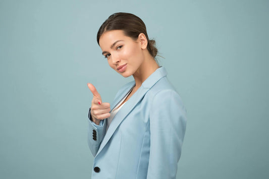 femme en tailleur qui montre la camera du doit en souriant