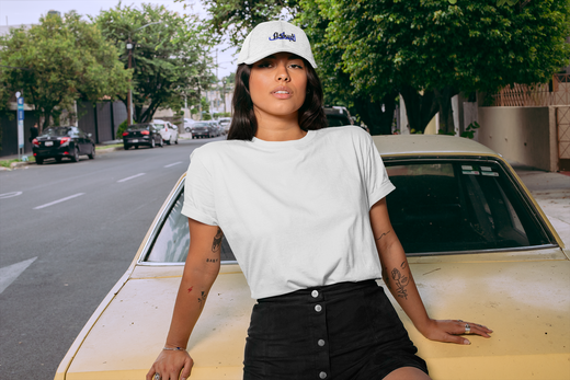 femme appuyée sur une voiture qui porte une casquette blanche