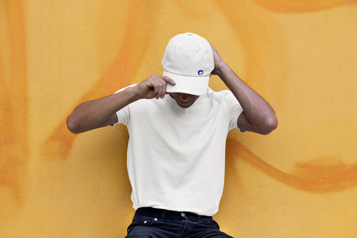 homme qui tient sa casquette Ayoun sur devant un mur jaune