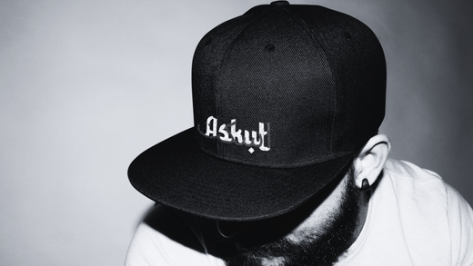 homme avec tête baissé portant casquette noir Ayoun écrit Askut