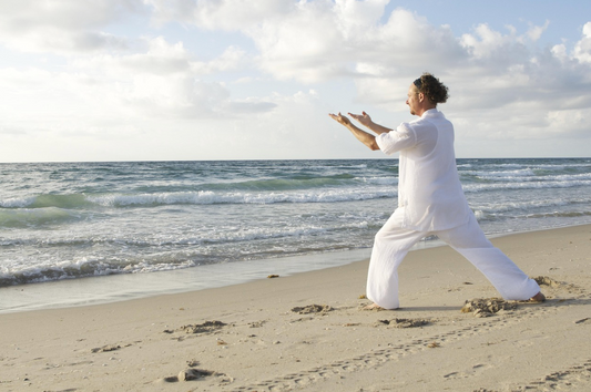 homme qui medite sur la plage habille en blanc