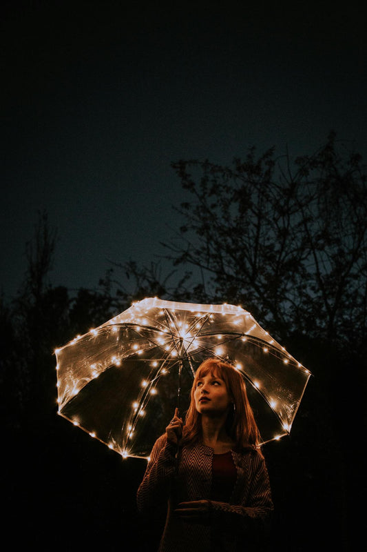 femme sous un parapluie éclairé la nuit