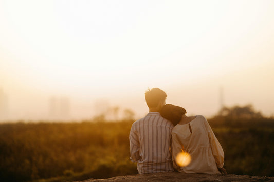 Un couple dans un champ regarde le couche du soleil